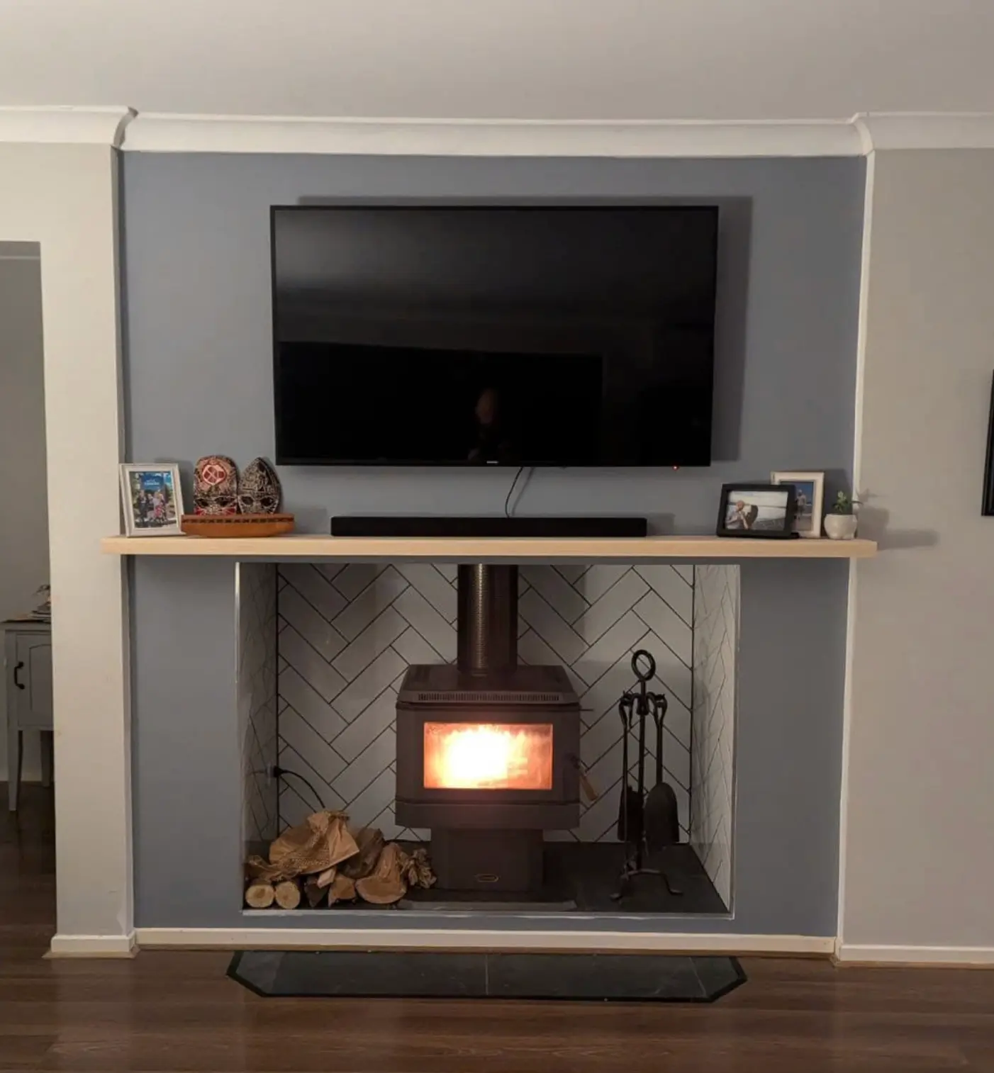 Renovated living room with a tiled fireplace feature wall and timber mantel
