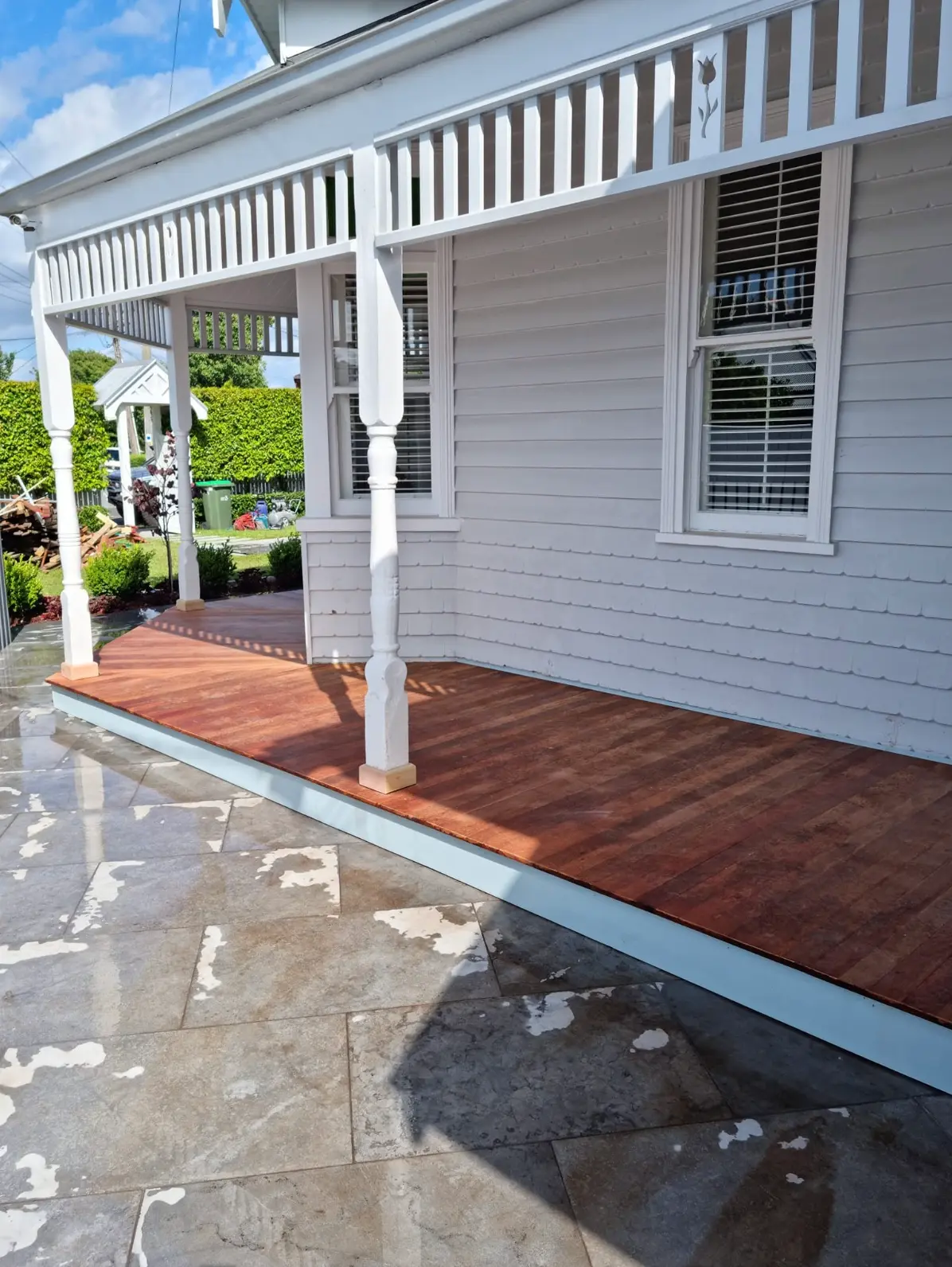 Restored front veranda with new hardwood flooring on a white weatherboard home