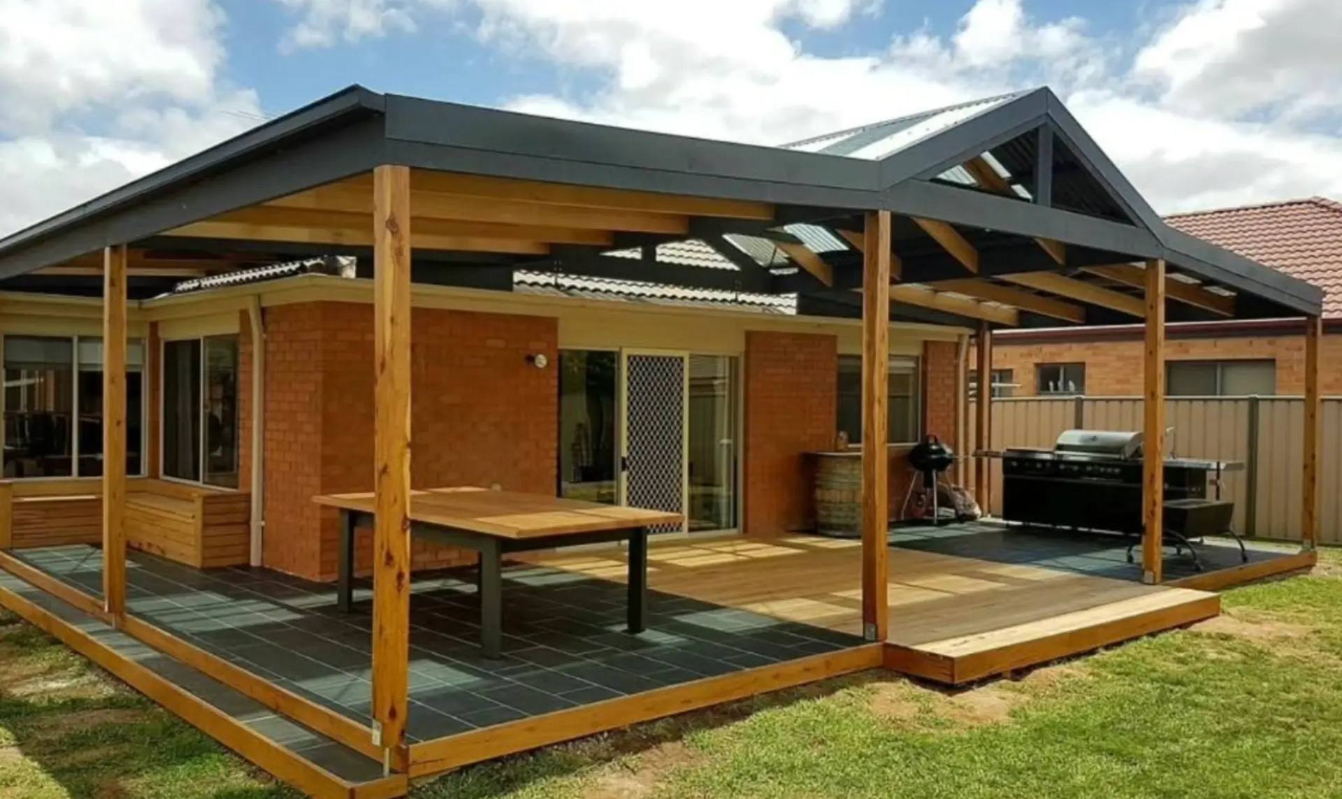 Gable roof pergola with timber posts over a paved and decked outdoor entertaining area